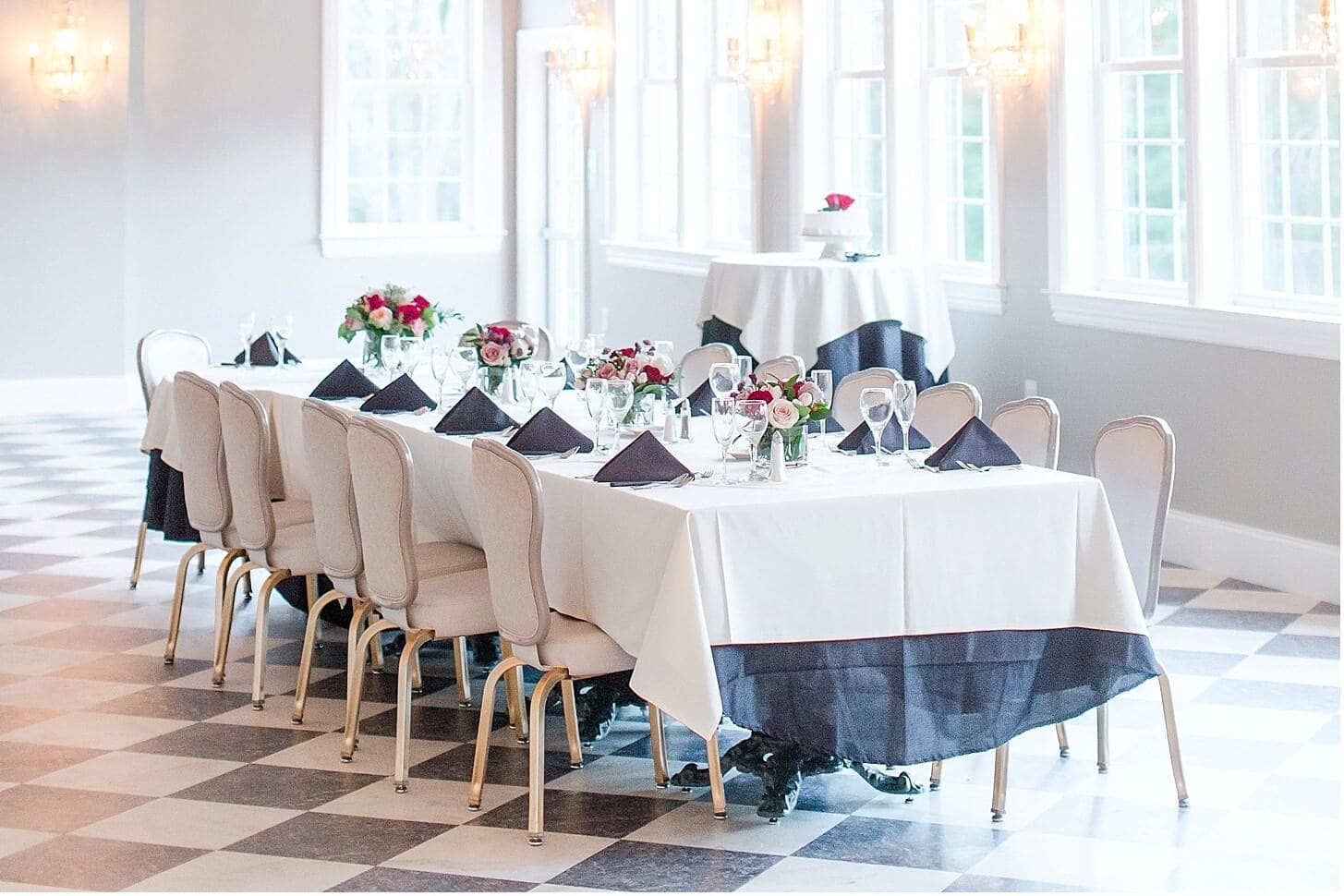 Long rehearsal dinner table with white linens and floral centerpieces at Cameron Estate Inn