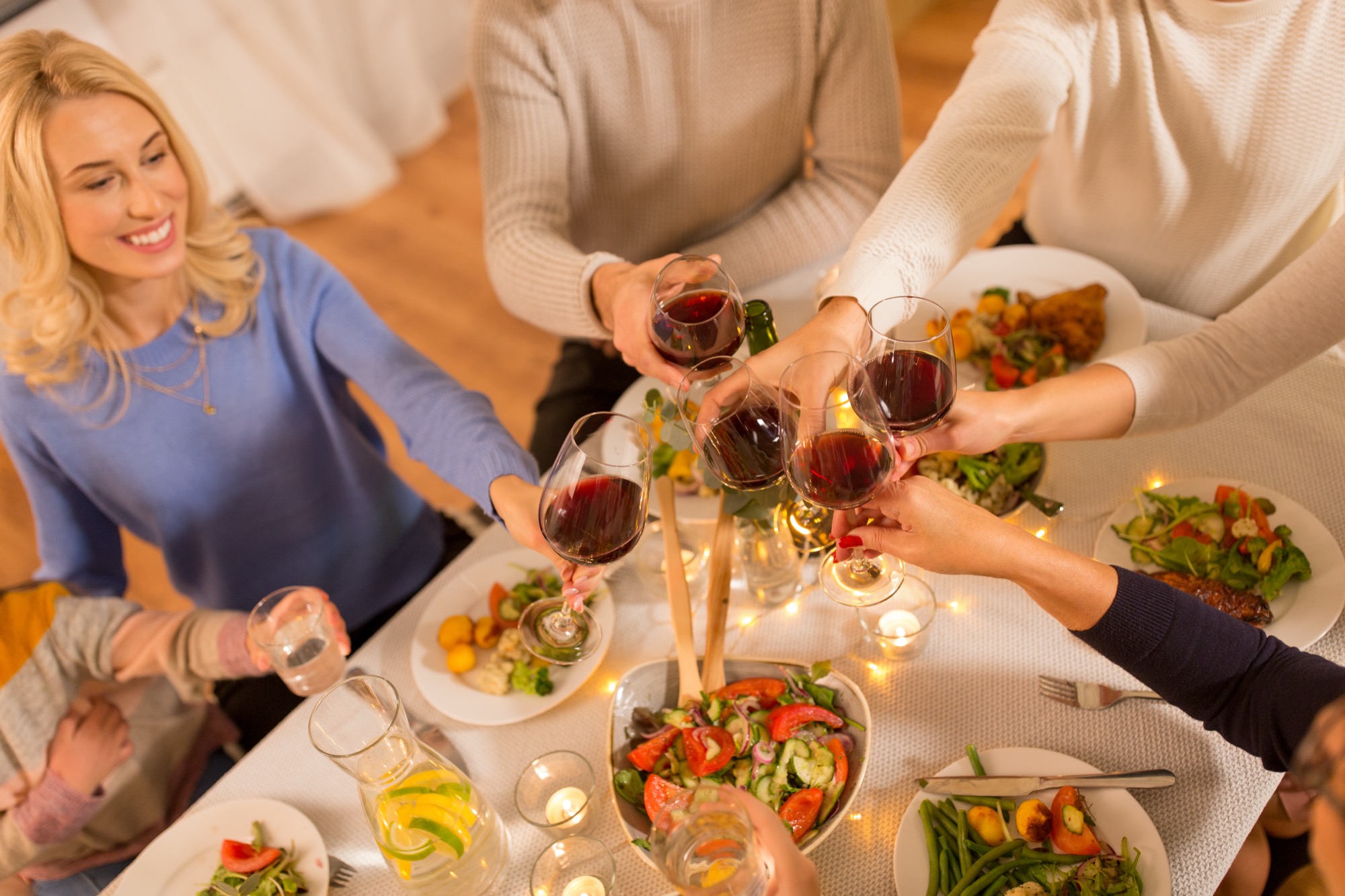 Family and friends raising glasses at a long rehearsal dinner table