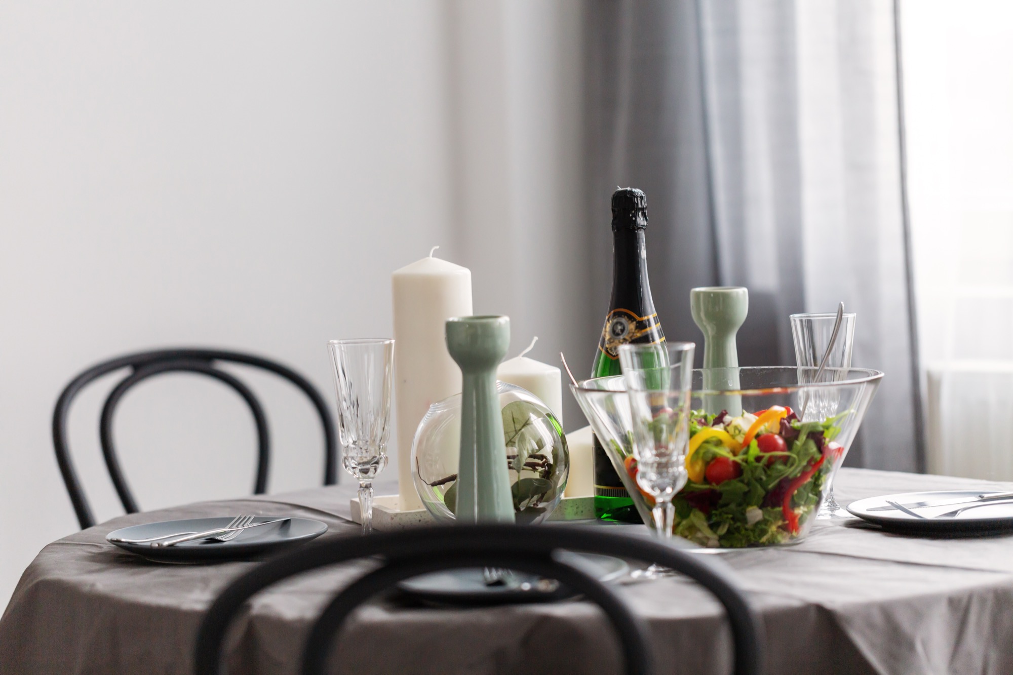 Small table set for a private rehearsal dinner with candles, salad, and champagne